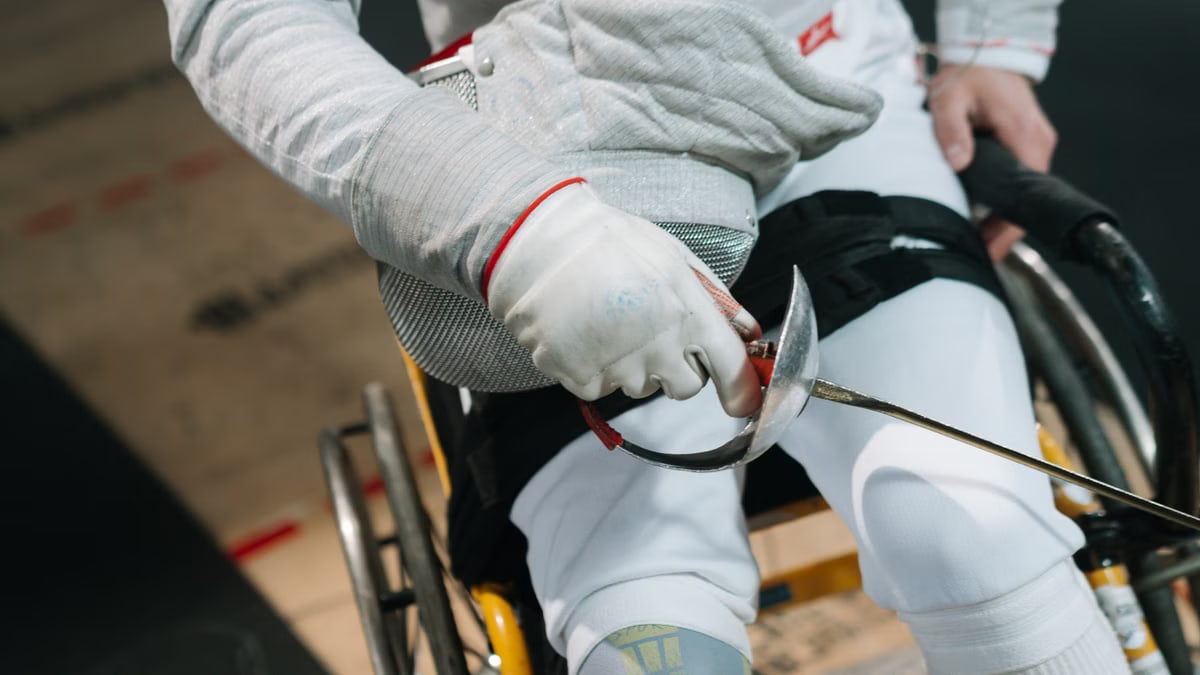 Close-up of a wheelchair fencer gripping a sabre, showcasing focus and determination in sport
